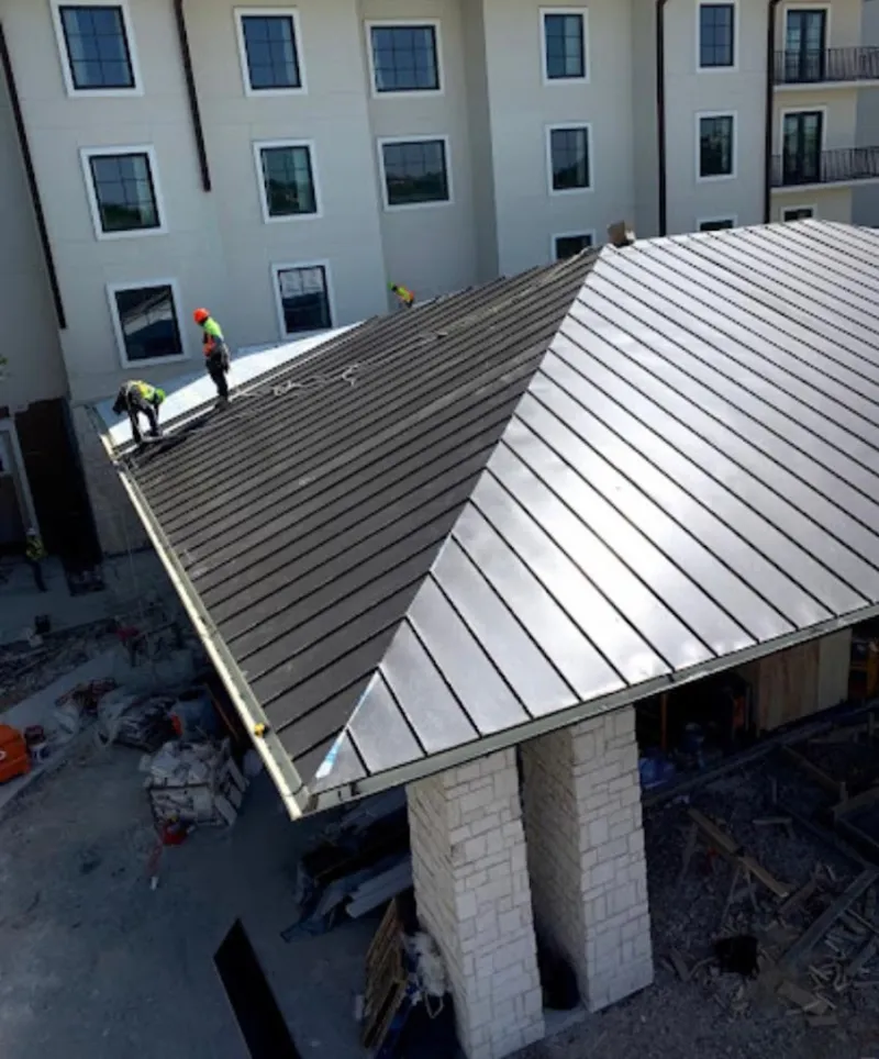 Crew installing standing seam metal roof panels on a commercial project in Brandon